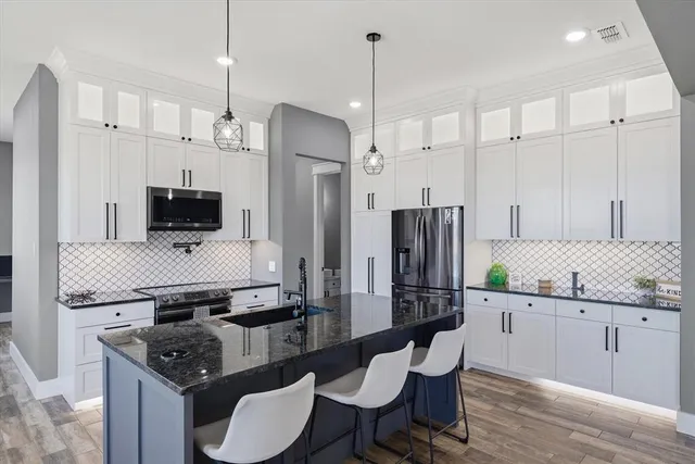 a kitchen with stainless steel appliances granite countertop a stove a sink a refrigerator and a wooden cabinets