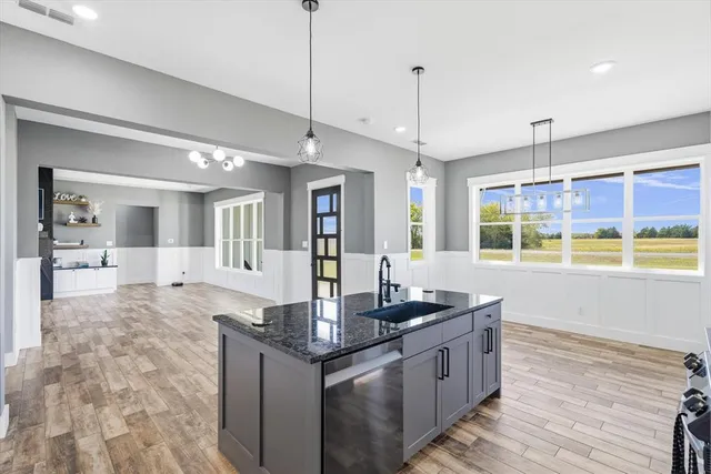 a kitchen with stainless steel appliances granite countertop a sink a counter space and wooden floor