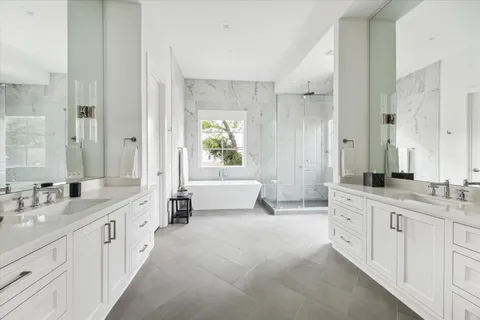 a large white bathroom with a double vanity sink a mirror and a bathtub