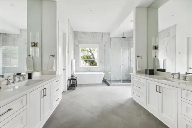 a large white bathroom with a double vanity sink a mirror and a bathtub