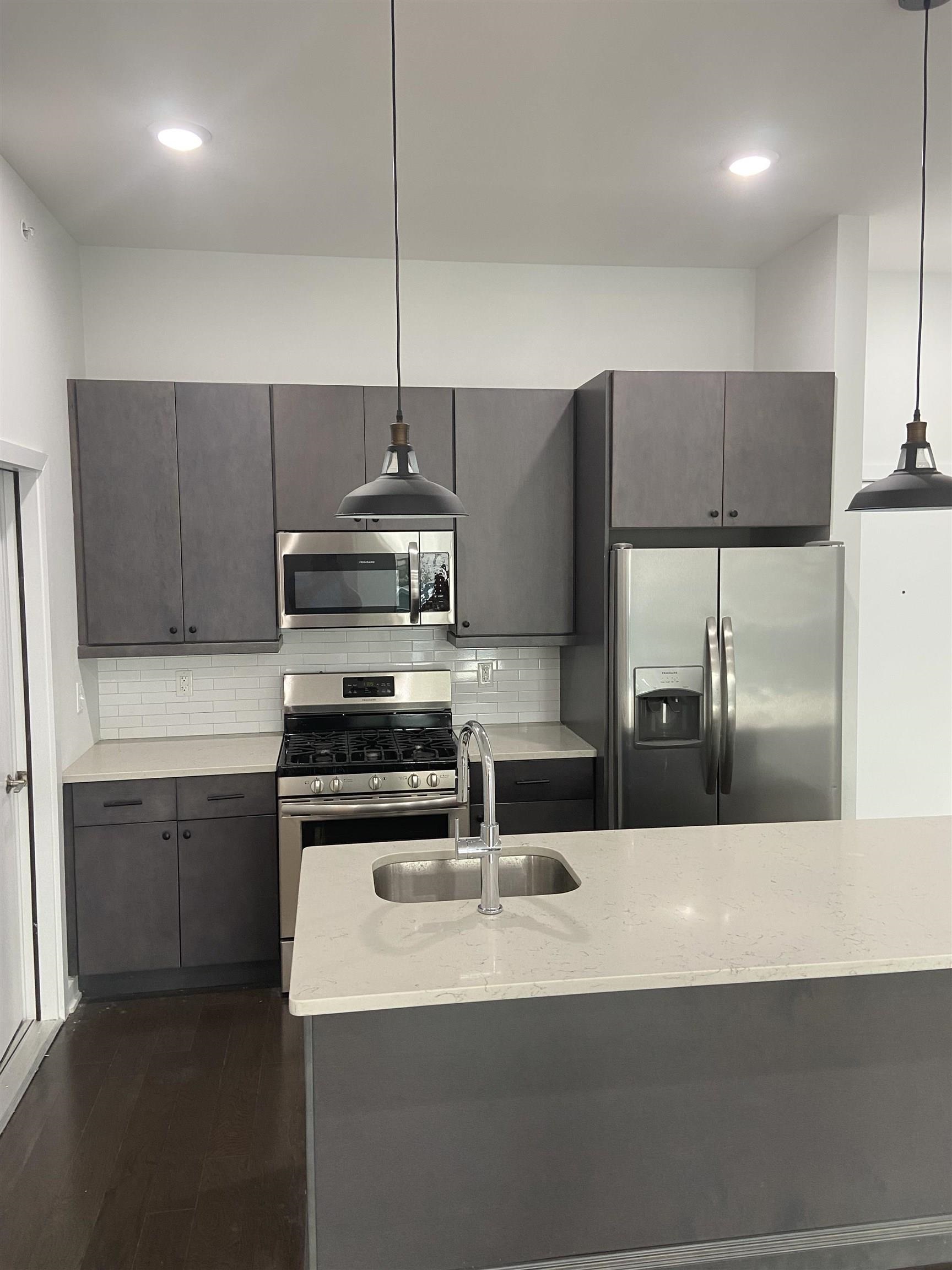 275 Broadway, Unit 302 Bayonne, NJ 07002 - Photo 11 of 13 a kitchen with stainless steel appliances a sink a stove a refrigerator and island