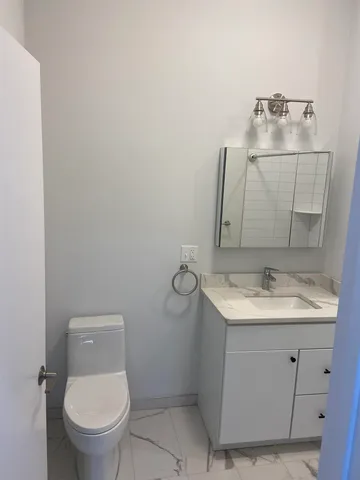 a bathroom with a granite countertop sink a toilet and mirror
