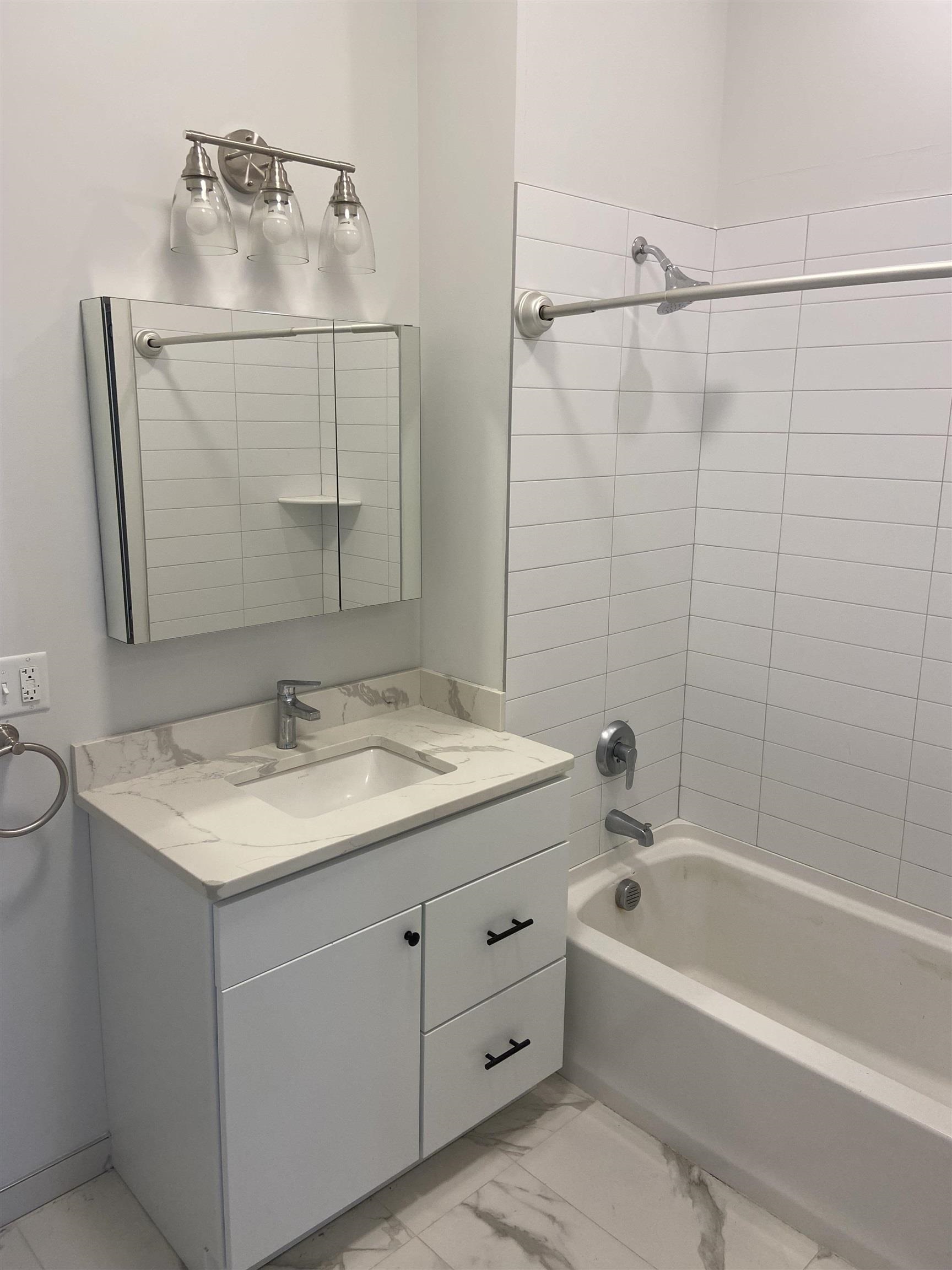 275 Broadway, Unit 302 Bayonne, NJ 07002 - Photo 13 of 13 a bathroom with a granite countertop sink a mirror and shower