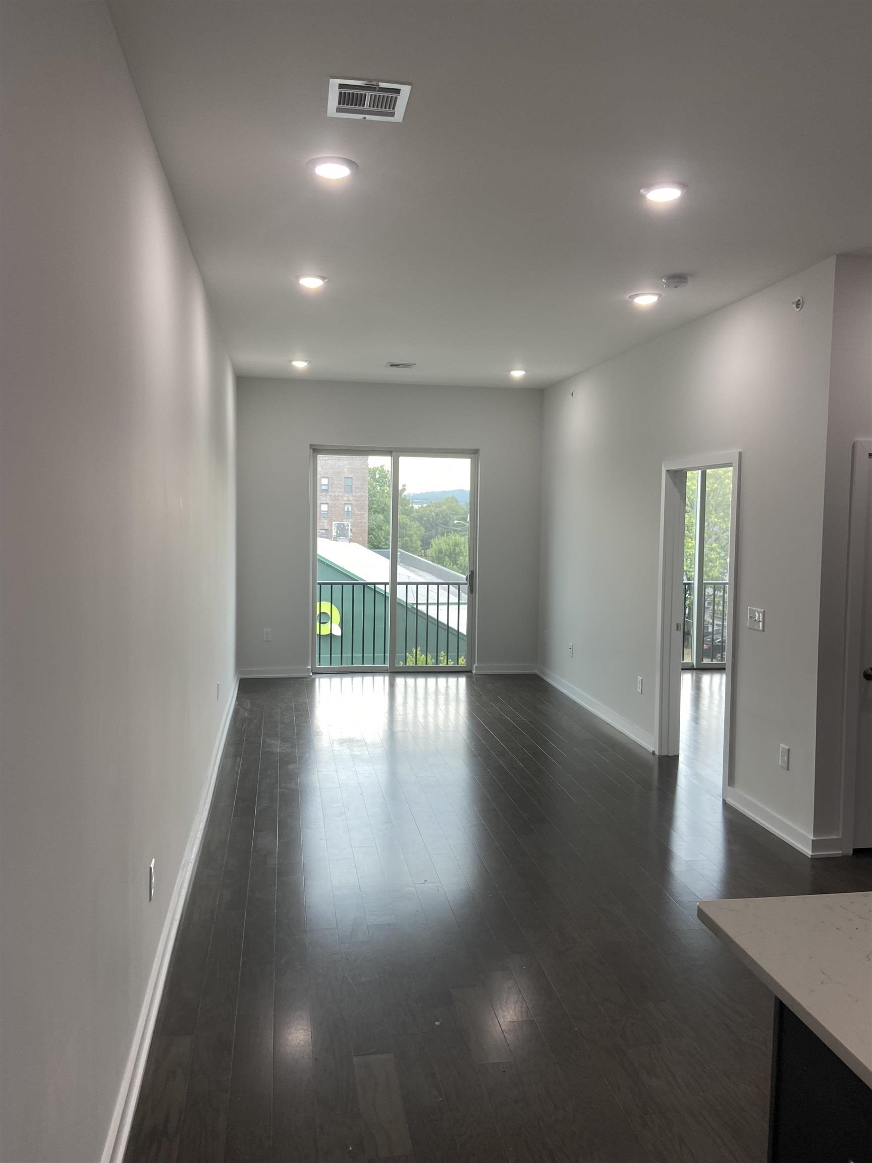 275 Broadway, Unit 302 Bayonne, NJ 07002 - Photo 3 of 13 an empty room with wooden floor and windows