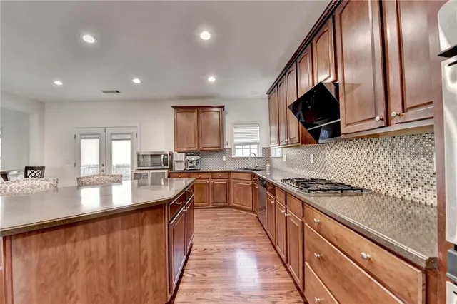 a kitchen with stainless steel appliances granite countertop a refrigerator a stove top oven a sink dishwasher and wooden cabinets with wooden floor