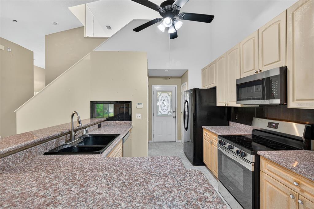 148 Lookout Drive Apollo Beach, FL 33572 - Photo 28 of 71 a kitchen with stainless steel appliances a sink a stove a microwave a sink a refrigerator white cabinets and wooden floor