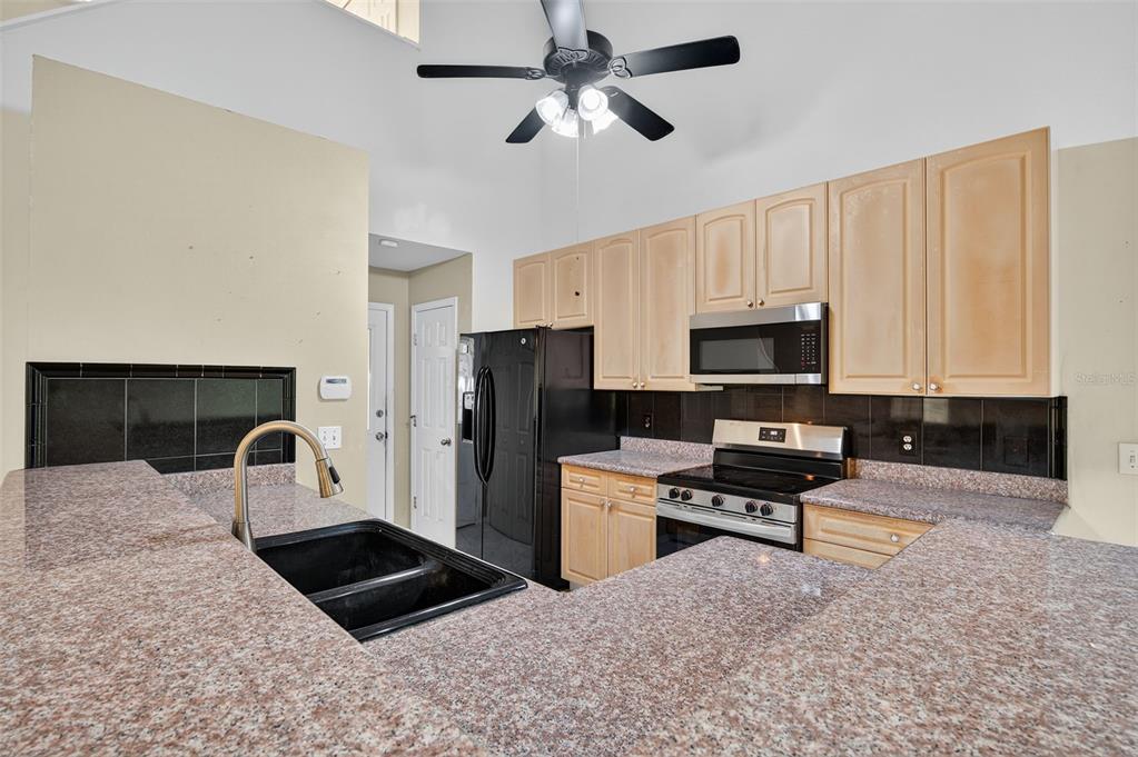 148 Lookout Drive Apollo Beach, FL 33572 - Photo 30 of 71 a kitchen with stainless steel appliances a stove a refrigerator a sink a microwave with white cabinets and wooden floor