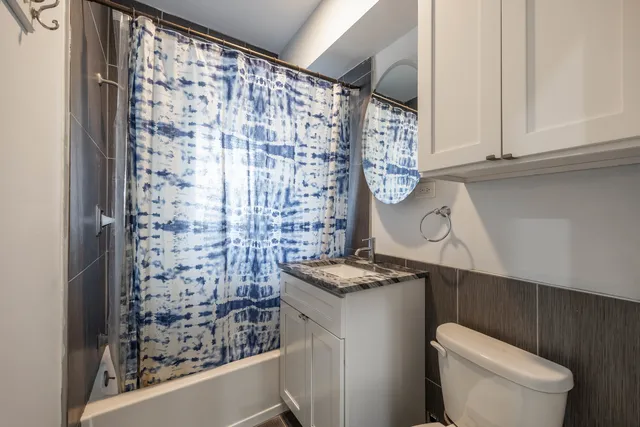 a bathroom with a granite countertop sink a toilet and a shower curtain