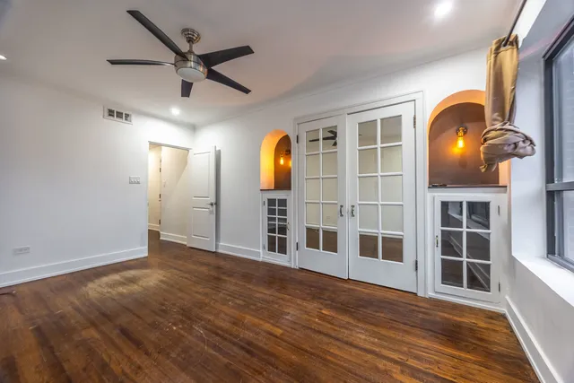 an empty room with wooden floor and windows