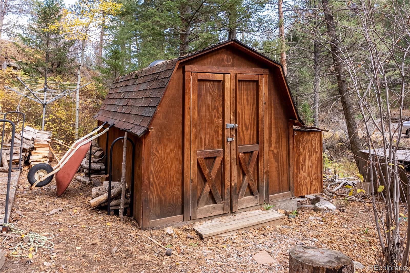10853 Twin Spruce Road Golden, CO 80403 - Photo 14 of 32 a view of a wooden house with large trees and wooden fence