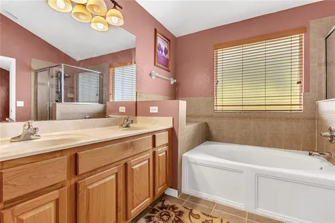 a bathroom with a granite countertop sink mirror vanity bathtub and next to a window