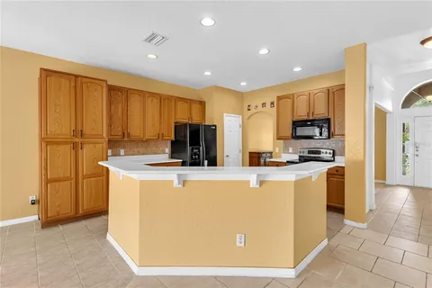 a view of kitchen with stainless steel appliances granite countertop refrigerator stove microwave and sink