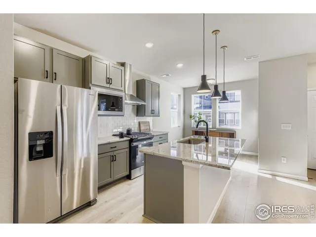 a kitchen with stainless steel appliances kitchen island granite countertop a refrigerator a stove a sink and a dining table with wooden floor