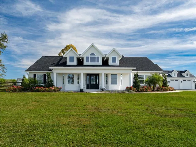a view of a white house with a big yard and large trees