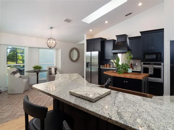 a kitchen with stainless steel appliances kitchen island granite countertop a table chairs and a refrigerator