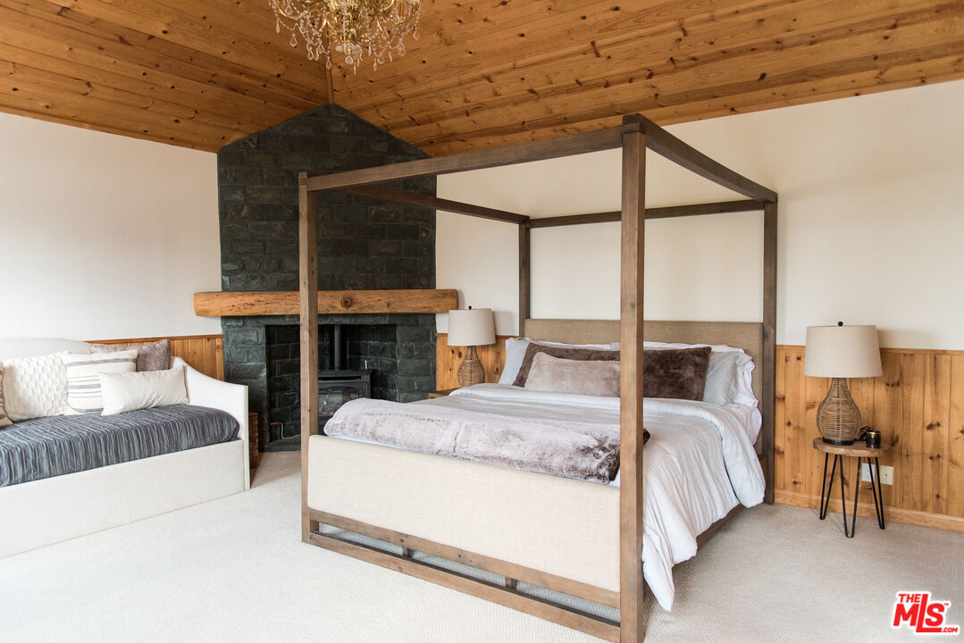 668 Cove Drive Big Bear Lake, CA 92315 - Photo 14 of 31 a large bedroom with a large bed and a chandelier