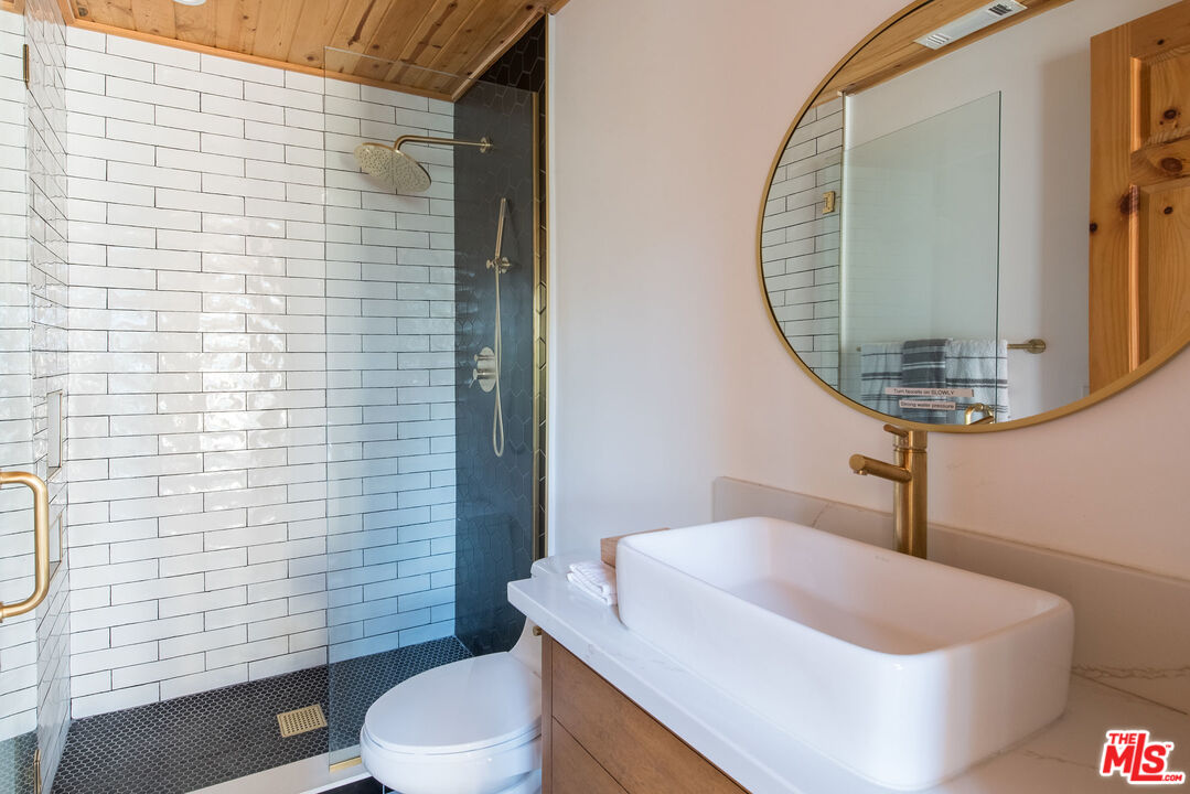 668 Cove Drive Big Bear Lake, CA 92315 - Photo 22 of 31 a bathroom with a sink a toilet and mirror