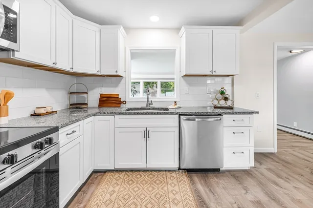 a kitchen with stainless steel appliances granite countertop a stove a sink and white cabinets