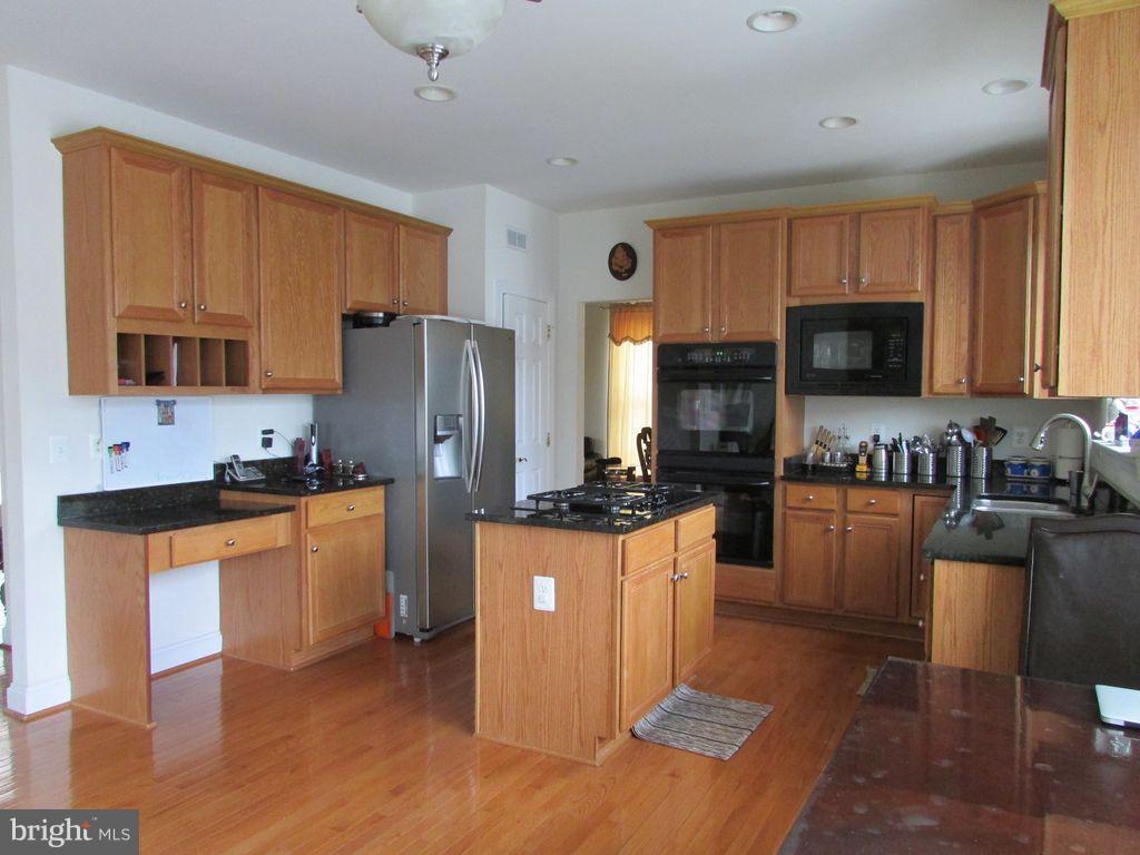 42770 Conquest Circle Brambleton, VA 20148 - Photo 13 of 70 a kitchen with stainless steel appliances granite countertop a stove a sink a refrigerator a microwave oven with granite countertops and cabinets