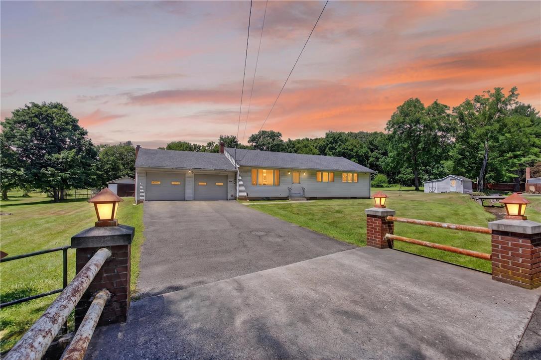 51 Reynolds Road Tamaqua, PA 18252 - Photo 3 of 71 A well-maintained ranch home with a two-car garage sits on a sprawling lawn under a vibrant sunset.