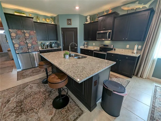 a kitchen with stainless steel appliances kitchen island granite countertop a refrigerator and a stove top oven