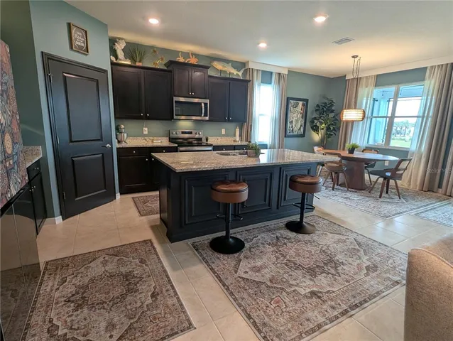 a living room with stainless steel appliances furniture a rug kitchen view and a chandelier