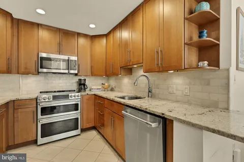 a kitchen with stainless steel appliances granite countertop wooden cabinets a stove top oven a sink and dishwasher