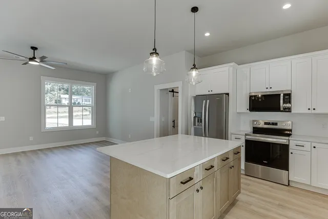 a view of kitchen with stainless steel appliances granite countertop cabinets and wooden floor