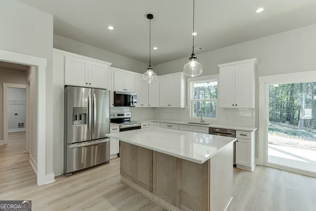 a kitchen with stainless steel appliances a sink a stove a refrigerator cabinets and wooden floor