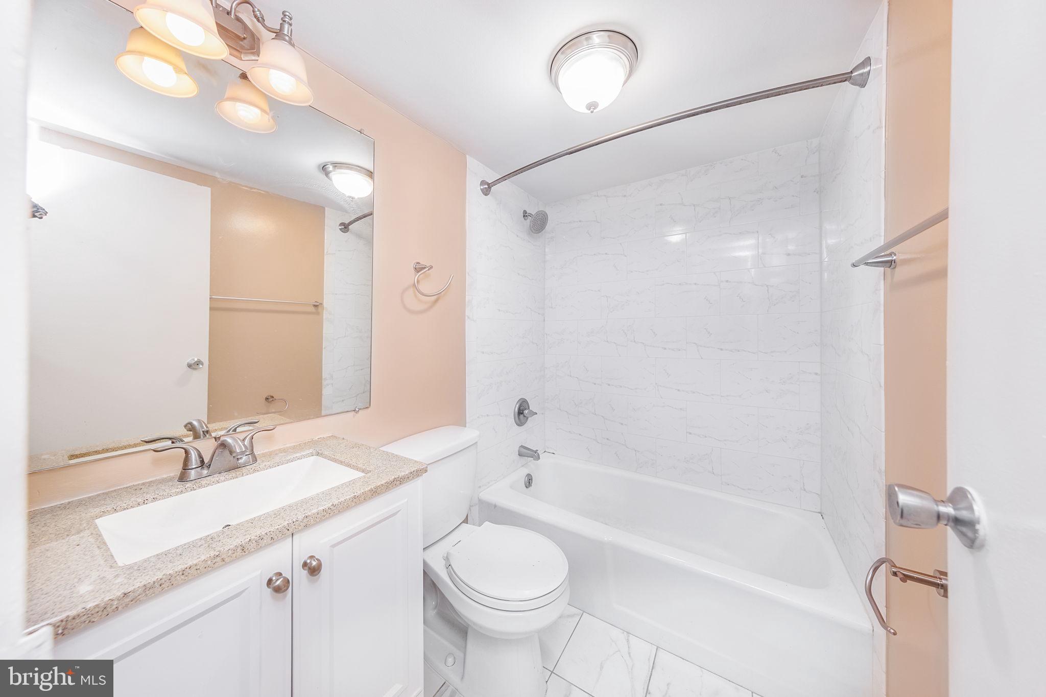 1260 21st Street Northwest, Unit 1004 Washington, DC 20036 - Photo 17 of 27 a bathroom with a granite countertop sink a toilet a mirror and shower