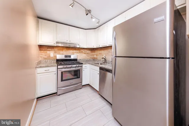 a kitchen with a refrigerator a stove top oven and cabinets