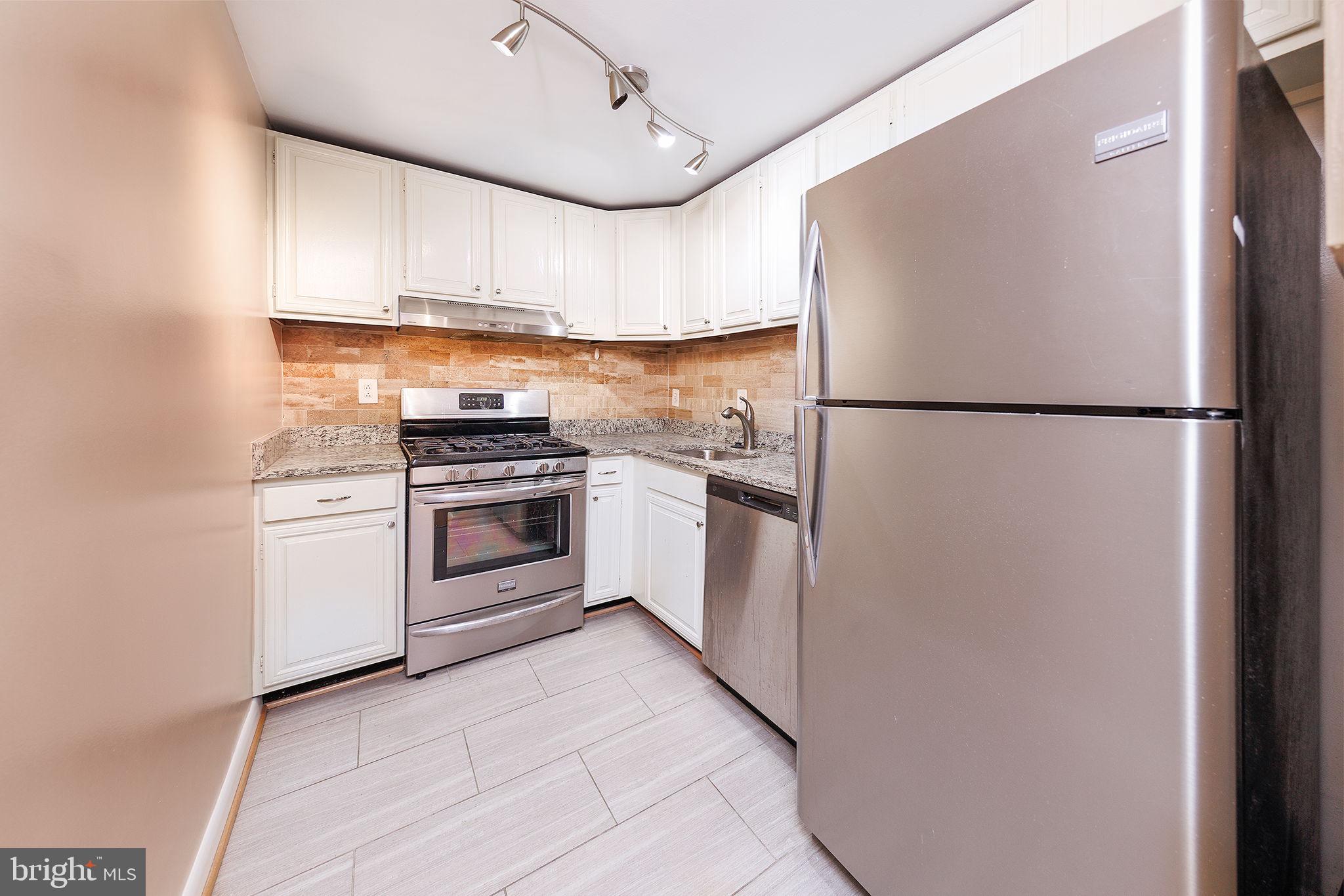 1260 21st Street Northwest, Unit 1004 Washington, DC 20036 - Photo 7 of 27 a kitchen with a refrigerator a stove top oven and cabinets