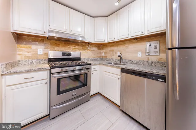 a kitchen with granite countertop cabinets stainless steel appliances and a sink