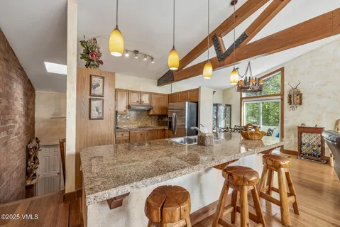 a dining hall with stainless steel appliances granite countertop a dining table chairs and chandelier