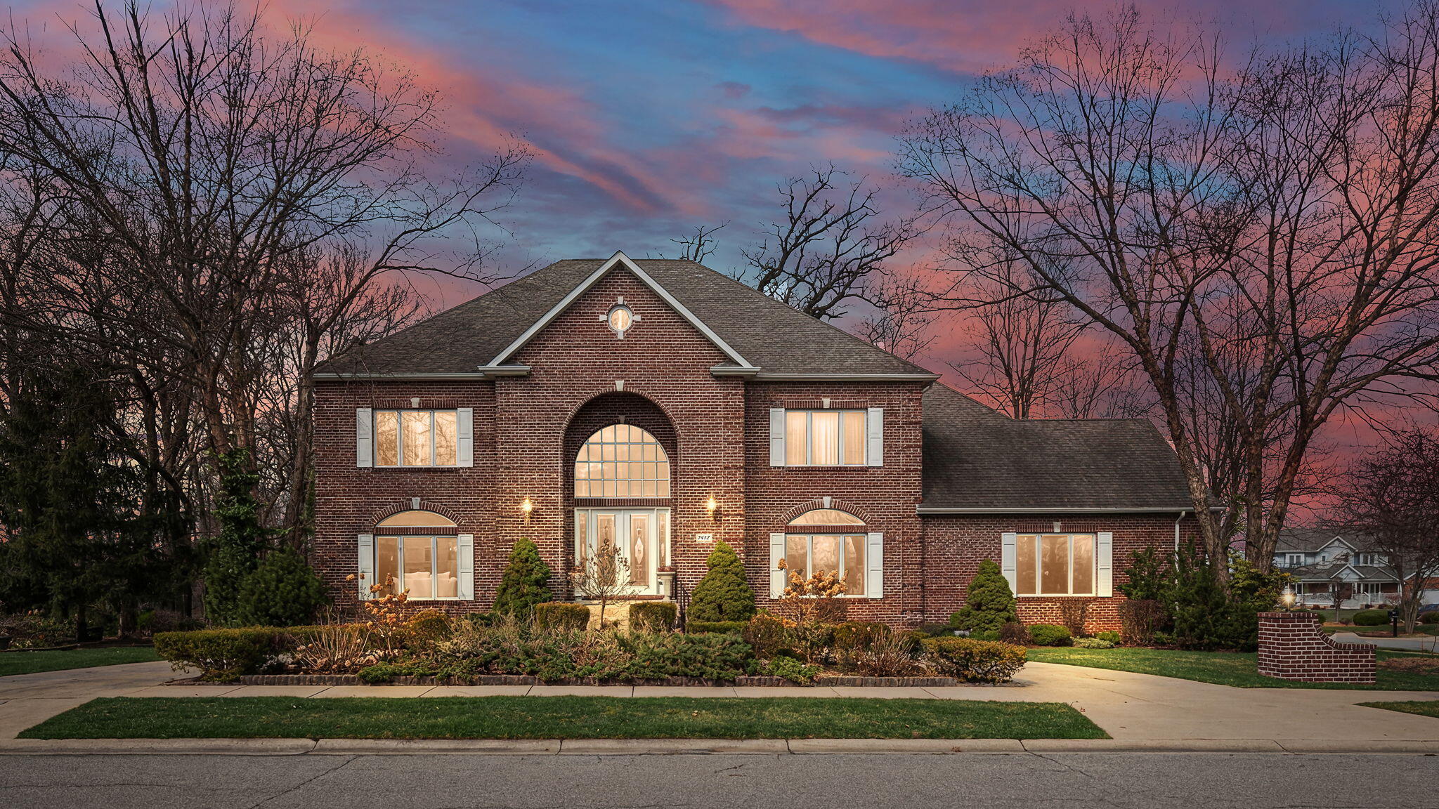 a front view of a house with lots of trees and plants