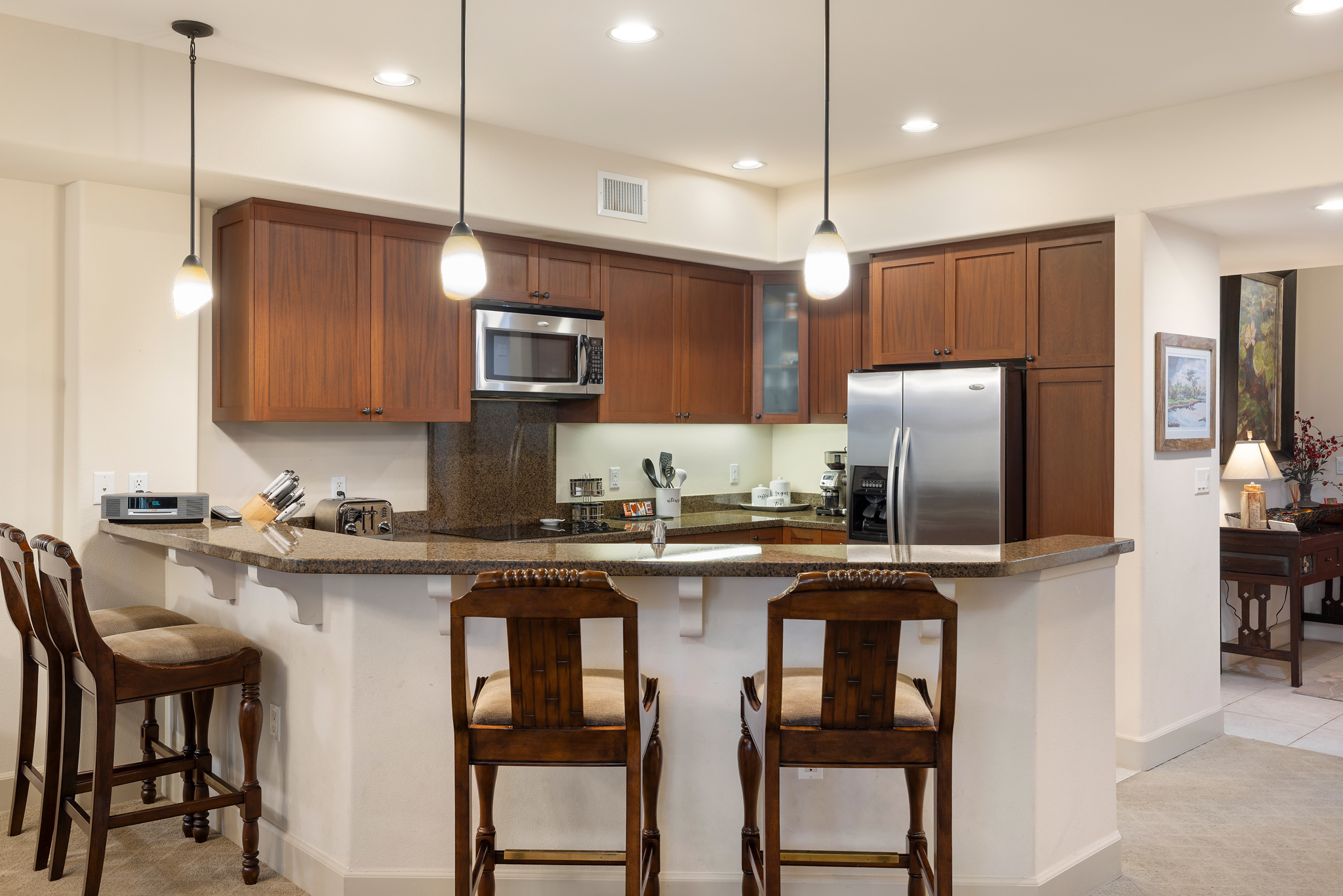 69-1033 Nawahine Place, Unit 4G Waikoloa, HI 96738 - Photo 9 of 26 a kitchen with stainless steel appliances granite countertop a stove top oven a refrigerator a sink and chairs