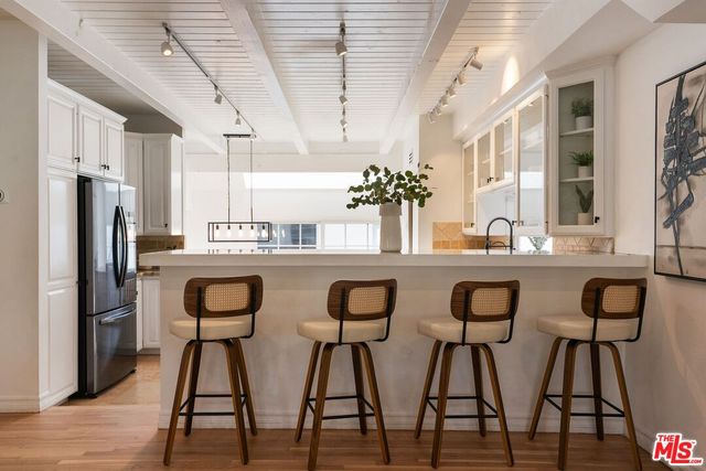 a kitchen with stainless steel appliances kitchen island granite countertop a dining table chairs and a refrigerator