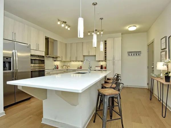 a kitchen with stainless steel appliances a table chairs wooden floors and white cabinets