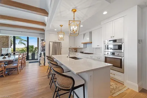 a kitchen with a dining table chairs stainless steel appliances and cabinets