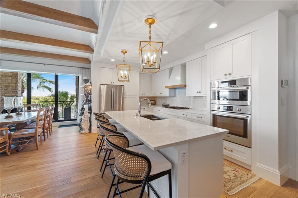 1135 3rd Avenue South, Unit 409 Naples, FL 34102 - Photo 15 of 44 a kitchen with a dining table chairs stainless steel appliances and cabinets