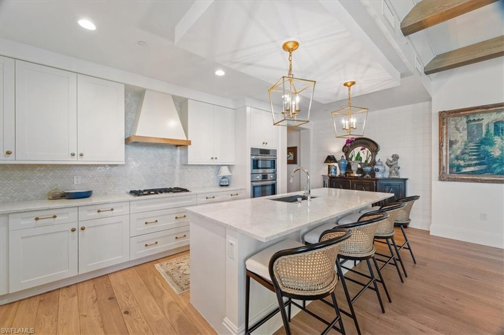 1135 3rd Avenue South, Unit 409 Naples, FL 34102 - Photo 16 of 44 a kitchen with stainless steel appliances granite countertop a kitchen island a stove a table and chairs in it