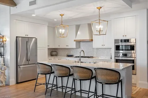 a kitchen with stainless steel appliances granite countertop a sink a stove a refrigerator and island with wooden floor