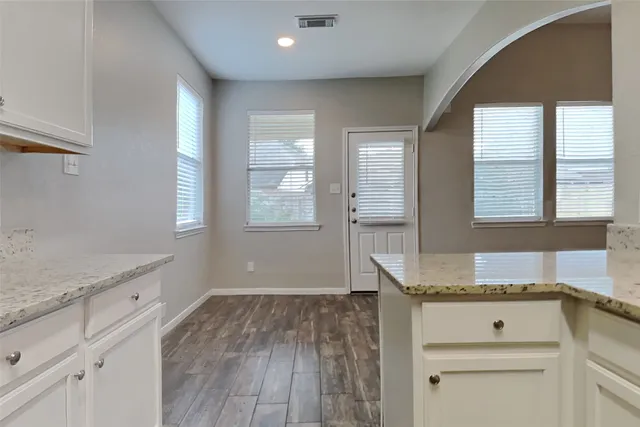 a kitchen with granite countertop white cabinets and wooden floor