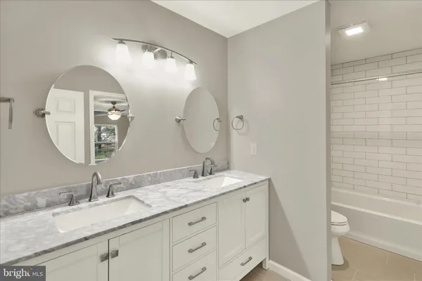 a spacious bathroom with a double vanity sink a mirror and a bathtub