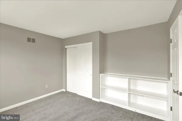 an empty room with chandelier fan and windows