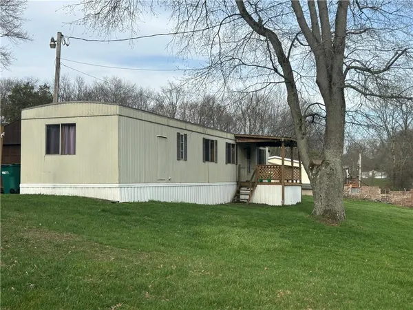 a view of a house with a big yard with large tree