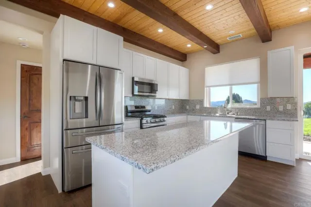 a kitchen with stainless steel appliances granite countertop a refrigerator a sink a stove a microwave and island