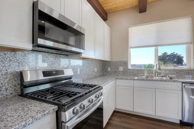 a kitchen with stainless steel appliances granite countertop a stove and a microwave