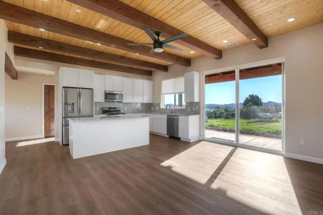a open kitchen with stainless steel appliances granite countertop a refrigerator a sink dishwasher a stove and white countertops with wooden floor