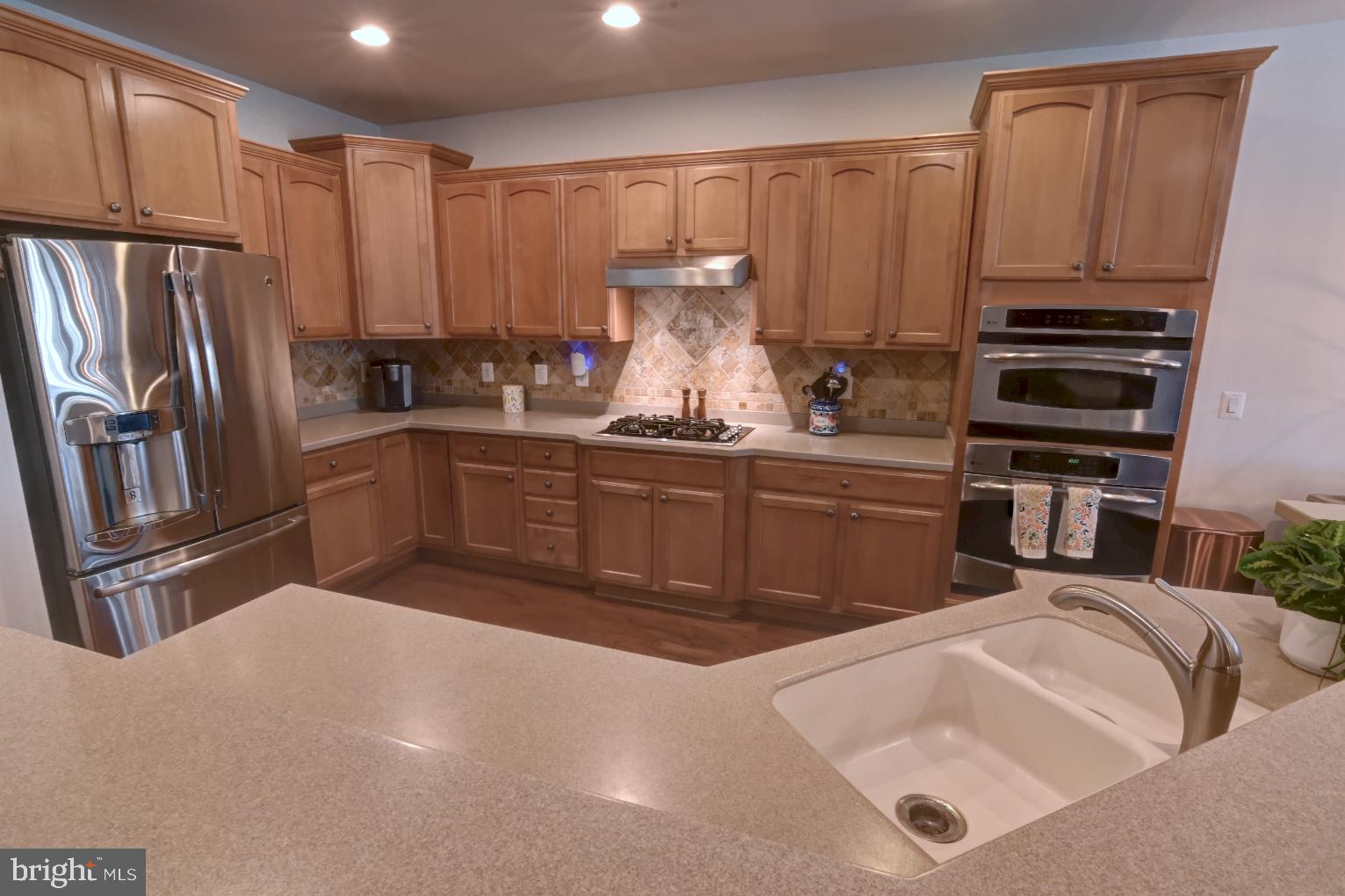 13170 Triple Crown Loop Gainesville, VA 20155 - Photo 22 of 71 a kitchen with stainless steel appliances a sink a stove a refrigerator cabinets and a counter top space